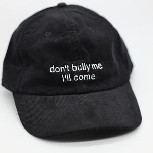 Könnte beinhalten: Eine schwarze Baseballkappe aus Cord mit weißer Stickerei, auf der "don't bully me I'll come" steht.