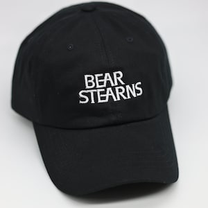 May include: A black baseball cap with a white embroidered logo that says "BEAR STEARNS".