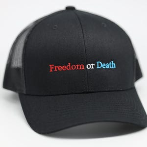 Może przedstawiać: Czarna czapka typu trucker z zakrzywionym daszkiem i siatkowym tyłem. Czapka ma wyszyty napis "Freedom or Death" w kolorze czerwonym i niebieskim. Klasyczny styl, odpowiedni do noszenia na co dzień.