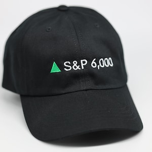 May include: Black baseball cap featuring the embroidered text "S&P 6,000" in white, with a green upward-pointing triangle. The cap has a curved peak and a button on top.