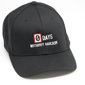 May include: Black baseball cap with a white embroidered design that says "0 DAYS WITHOUT SARCASM" with a red and white square around the "0".