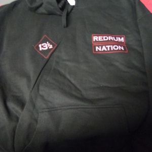 May include: Black hooded sweatshirt with red text that reads "Redrum Nation" and a red diamond with the text "13 1/2" on the front.