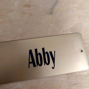 Gold plastic stall plate with black letters