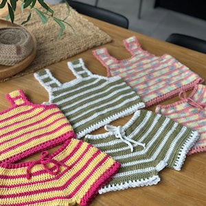 May include: Four crocheted crop tops and shorts sets in various color combinations. The sets feature yellow, pink, green, and white stripes.