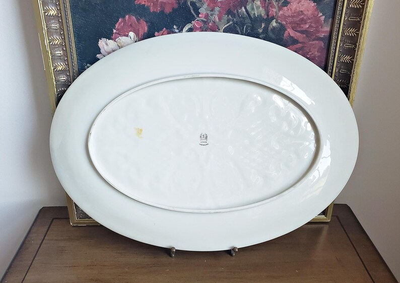 May include: White oval serving platter with a raised, textured design. The platter has a small mark on the bottom and a stamp that reads "Made in Germany".