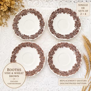 May include: Four white ceramic saucers featuring a brown transferware pattern of grapevines and wheat around the rim. The text on the image reads: BOOTHS VINE & WHEAT BROWN ENGLISH EARTHENWARE, SINGLE OR SETS OF 2 &middot; 4, REPLACEMENT SAUCERS DISCONTINUED PATTERN.
