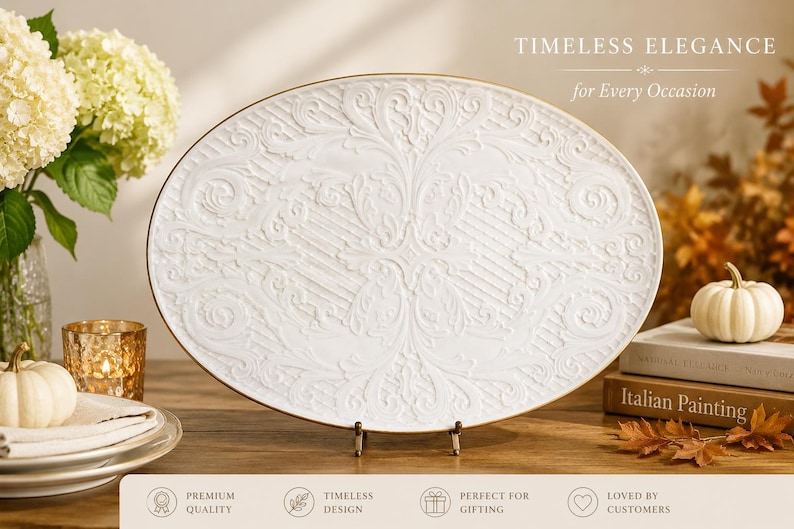 K&ouml;nnte beinhalten: Eine ovale wei&szlig;e Servierplatte mit einem erhabenen, komplizierten Reliefmuster und einem d&uuml;nnen Goldrand. Die Platte steht auf einem kleinen Metallst&auml;nder. Der Text auf dem Bild lautet: TIMELESS ELEGANCE for Every Occasion.