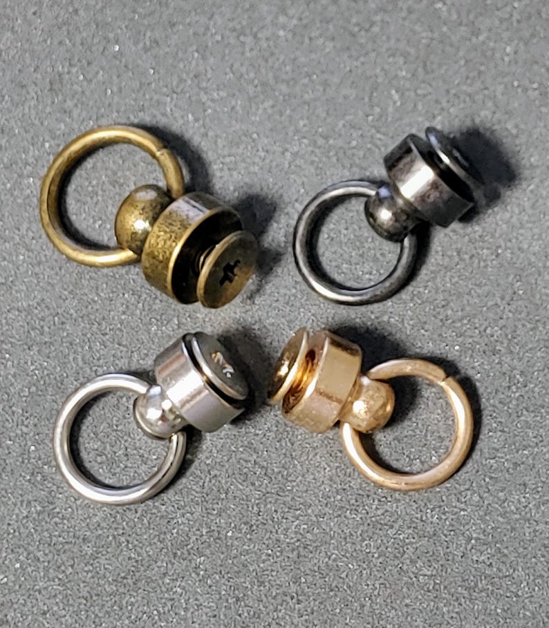 May include: Four metal swivel snap hooks with different finishes: gold, silver, brass, and black. Each hook has a small ring and a screw-on cap.