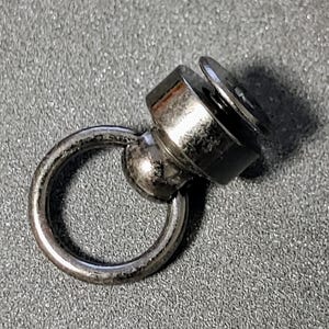 May include: A silver swivel snap hook with a round ring. The hook has a small screw on the top.