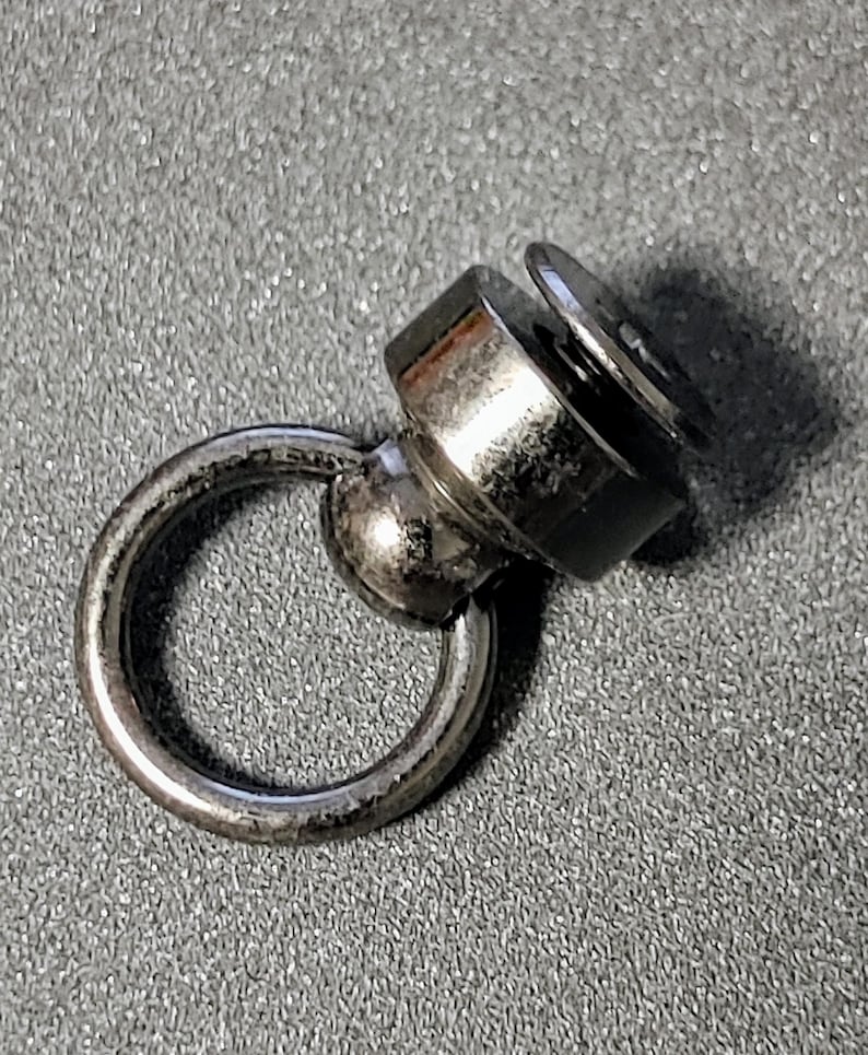 May include: A silver swivel snap hook with a round ring. The hook has a small screw on the top.