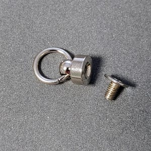 May include: Silver swivel snap hook with a ball bearing and a screw-on base. The base has a threaded hole for attaching to a surface.