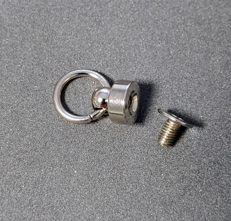 May include: Silver swivel snap hook with a ball bearing and a screw-on base. The base has a threaded hole for attaching to a surface.