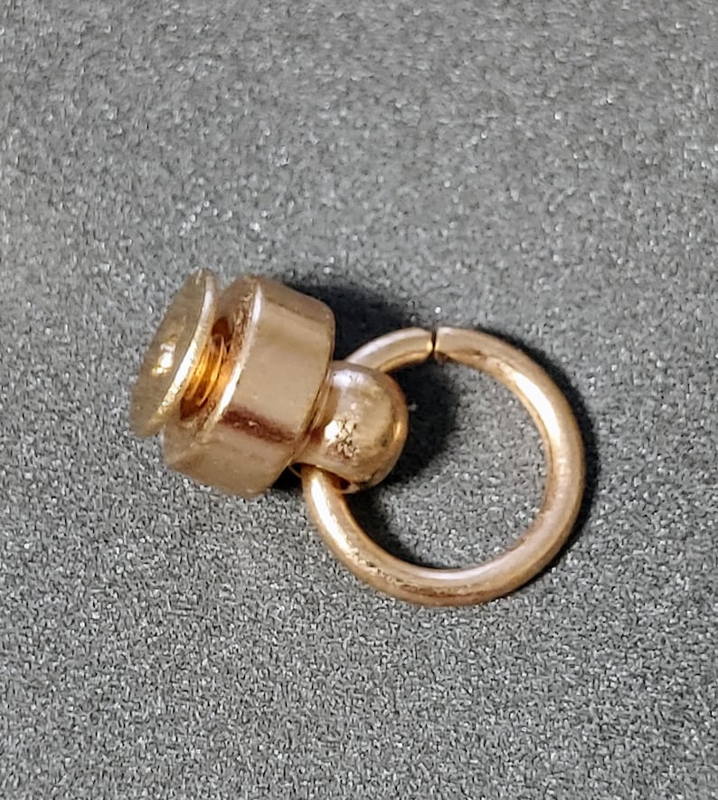 May include: Gold-toned metal swivel snap hook with a screw-on closure. The hook is attached to a small, round ring.