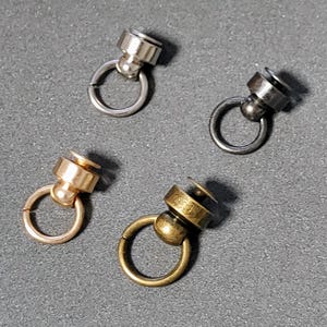May include: Four swivel snap hooks in different finishes: silver, black, gold, and antique brass. Each hook has a small ring and a swiveling ball.