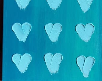 May include: A teal canvas painting with nine light blue hearts painted in a grid pattern.
