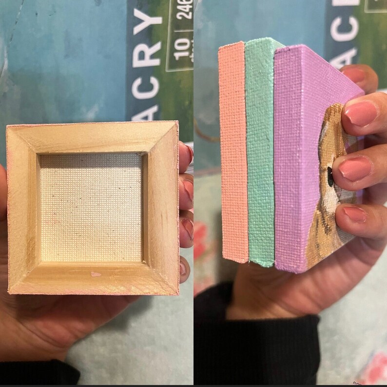 May include: Three small canvases with painted edges in pink, light green, and purple. The canvases are stacked on top of each other. The front canvas has a painting of a dog's face.