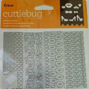 May include: A set of four Cricut Cuttlebug die sets for crafting. The dies feature a variety of designs, including bows, shoes, lips, and crowns. The dies are made of metal and are designed to be used with a Cricut Cuttlebug machine.