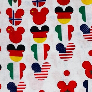 Puede incluir: Tela blanca con un patrón repetido de orejas de Mickey Mouse. Cada oreja está llena con la bandera de un país diferente, incluidos Estados Unidos, Canadá, México, Alemania, China, Marruecos, Noruega, Italia y Japón.
