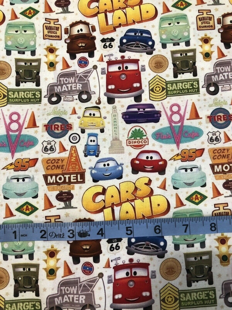 Pu&ograve; includere: Un tessuto colorato con un motivo ripetitivo di auto, camion e altri veicoli del film Cars della Disney Pixar. Il tessuto include il testo "Cars Land" e vari altri testi del film, come "Tow Mater" e "Cozy Cone Motel".