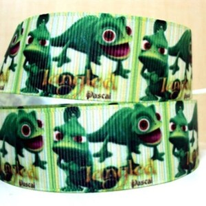 Puede incluir: Cinta verde y blanca con un patrón repetido de un camaleón de dibujos animados con el texto "Tangled" y "Pascal" en ella.