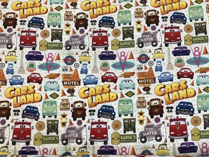 Pu&ograve; includere: Un tessuto bianco con un motivo ripetuto di immagini a tema Cars Land. Le immagini includono auto, camion, cartelli e le parole "Cars Land".