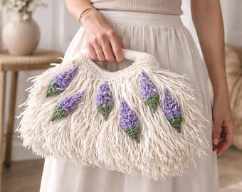 ラベンダーの花柄があしらわれた白いラフィア素材のクロシェバッグ、ボヘミアン風フリンジ付きサマーハンドバッグ