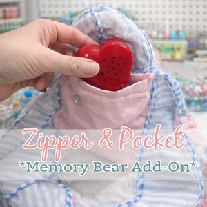 May include: A red heart-shaped sound module with small holes is placed inside a pink pocket. The pocket is sewn onto a blue and white striped fabric. The text "Zipper & Pocket *Memory Bear Add-On*" is displayed.
