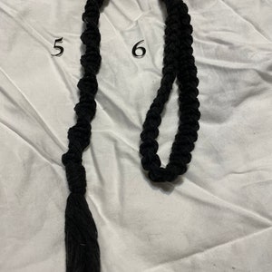 May include: Two black macrame keychains with silver key rings. The keychain on the left has a tassel at the end. The keychain on the right has a loop at the end.