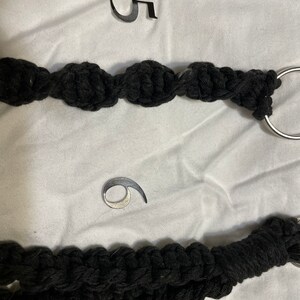 May include: Two black rope keychains with silver metal rings. The keychain on top has the number "5" on a white background. The keychain on the bottom has the number "6" on a white background.