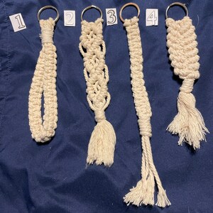 May include: Four handmade macrame keychains with different patterns and a tassel at the bottom. The keychains are numbered 1 through 4.