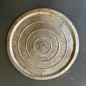 May include: A silver metal safety ring pot cover with the text "SAFETY RING POT COVER", "KEEPS FOOD WARM SAVER", and "ONE ONES SAFETY RING" printed on it.