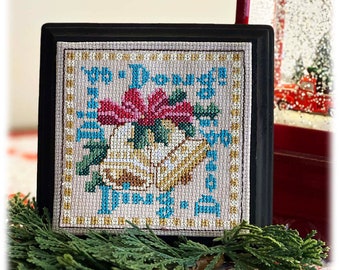 Puede incluir: Un diseño de punto de cruz enmarcado que presenta una poinsettia roja y dos campanas doradas con el texto "The Joy of Christmas" en letras azules y doradas.