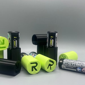 May include: A close-up of several black and green battery cases with the text "USB Lithium 2Ah" on the batteries. The cases have a green "R" logo on them.