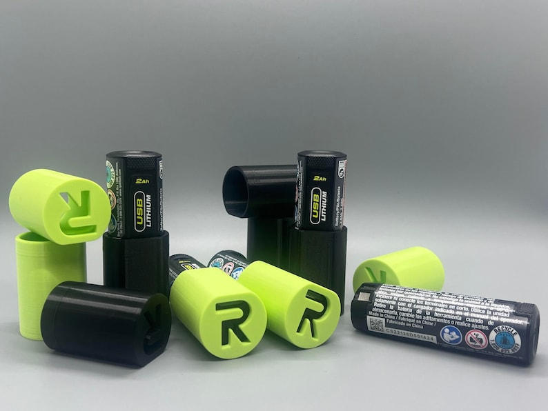 May include: A close-up of several black and green battery cases with the text "USB Lithium 2Ah" on the batteries. The cases have a green "R" logo on them.