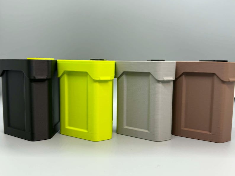 Op de afbeelding: Vier rechthoekige opbergbakken op een rij, met een matte afwerking en een verzonken paneelontwerp. De bakken zijn zwart, neongeel, lichtgrijs en bruin van kleur, elk voorzien van een klein zwart vierkant deksel aan de bovenzijde.