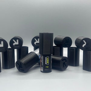 May include: A group of ten black plastic caps with a cut-out design. The caps are arranged in a circle around a black and silver USB rechargeable lighter. The lighter has the text "USB Rechargeable" and "2.4A" printed on it.