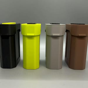 Op de afbeelding: Vier rechthoekige opbergcontainers staan op een rij. De containers zijn zwart, neongeel, lichtgrijs en bruin. Elke eenheid heeft een plat deksel met een klein zwart of geel accentstuk en een verticaal, licht getextureerd lichaam.