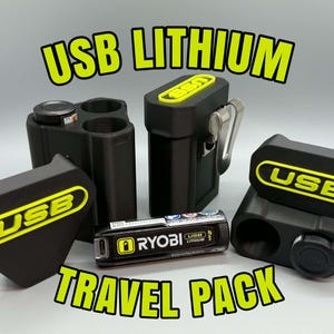 Op de afbeelding: Een zwarte Ryobi USB Lithium reisset met twee zwarte opbergcases met gele USB-logo's, een metalen riemclip en &eacute;&eacute;n cilindrische Ryobi USB Lithium batterij. De tekst USB LITHIUM TRAVEL PACK wordt in het geel weergegeven.