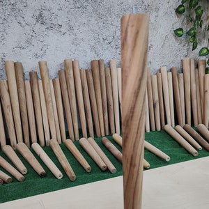 Puede incluir: Primer plano de una pata de mesa de madera con acabado de veta de madera natural. La pata es redonda y tiene una forma ligeramente cónica. La pata está sobre una superficie de madera clara.