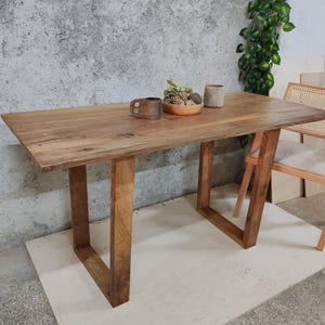 Puede incluir: Una mesa de madera r&uacute;stica con un acabado de madera natural y patas rectangulares simples. La mesa est&aacute; hecha de madera maciza y tiene un dise&ntilde;o de borde vivo. La mesa es perfecta para un comedor o una cocina.