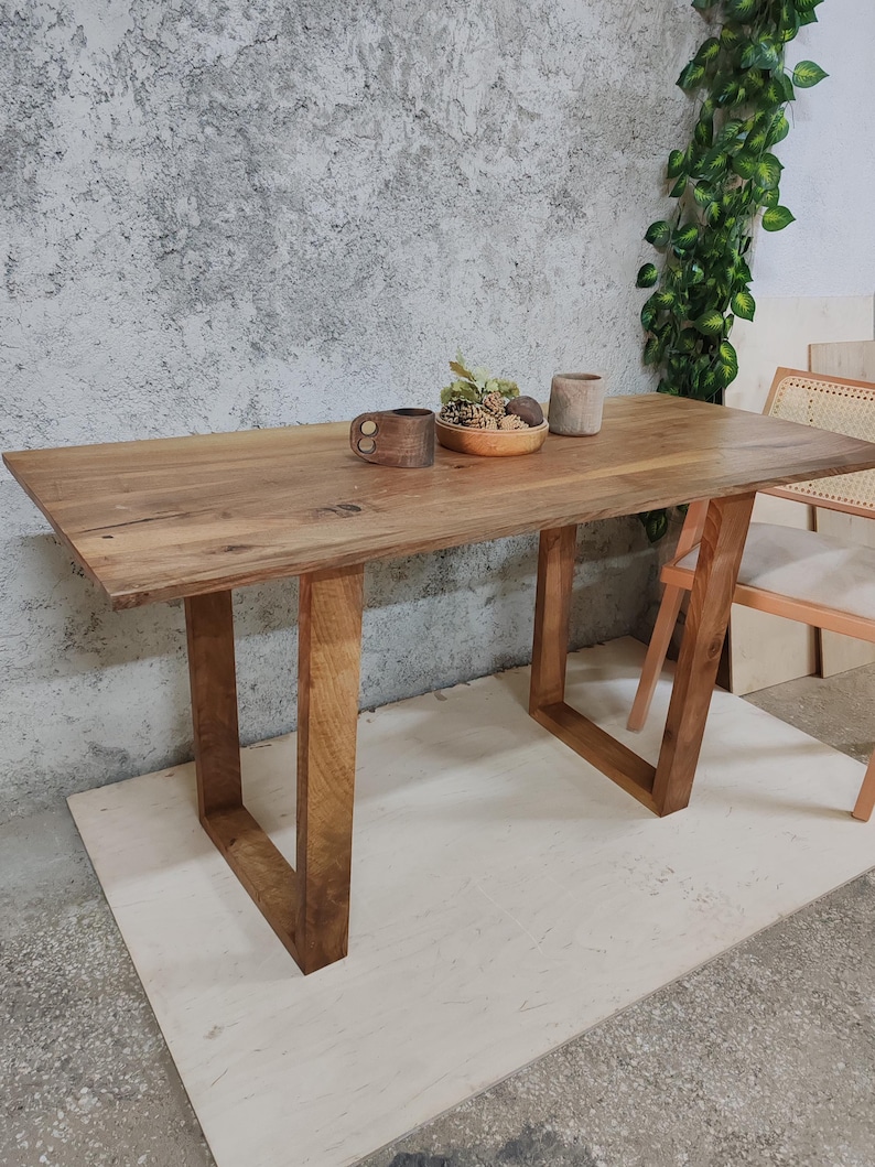 Puede incluir: Una mesa de madera r&uacute;stica con un acabado de madera natural y patas rectangulares simples. La mesa est&aacute; hecha de madera maciza y tiene un dise&ntilde;o de borde vivo. La mesa es perfecta para un comedor o una cocina.
