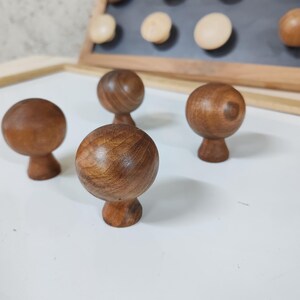 May include: Four wooden knobs with a round top and a small base. The knobs are a dark brown color and have a smooth, polished finish.