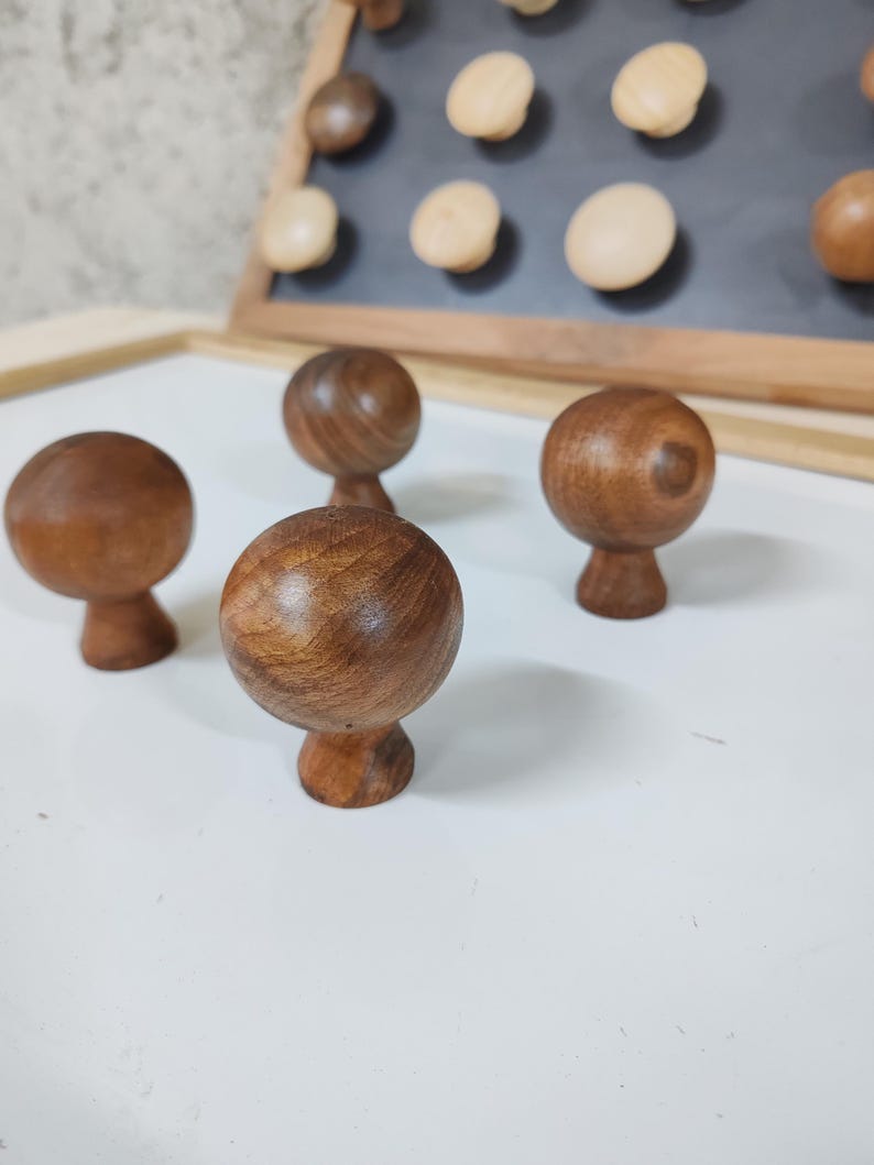 May include: Four wooden knobs with a round top and a small base. The knobs are a dark brown color and have a smooth, polished finish.