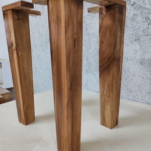 May include: Three wooden table legs with a dark brown stain. The legs are rectangular in shape and have a slightly tapered design.
