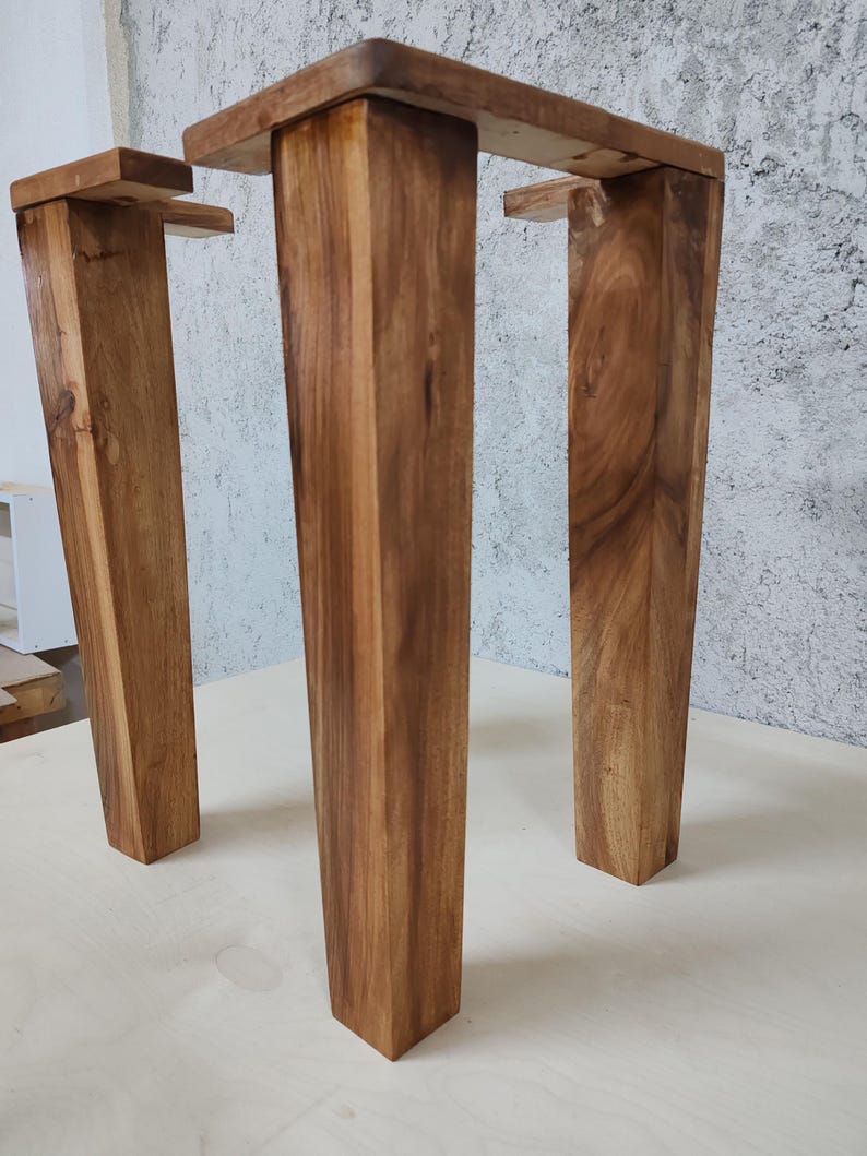 May include: Three wooden table legs with a dark brown stain. The legs are rectangular in shape and have a slightly tapered design.