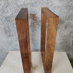 Puede incluir: Dos patas de mesa de madera con un acabado de madera natural. Las patas son de forma rectangular y tienen un aspecto r&uacute;stico.