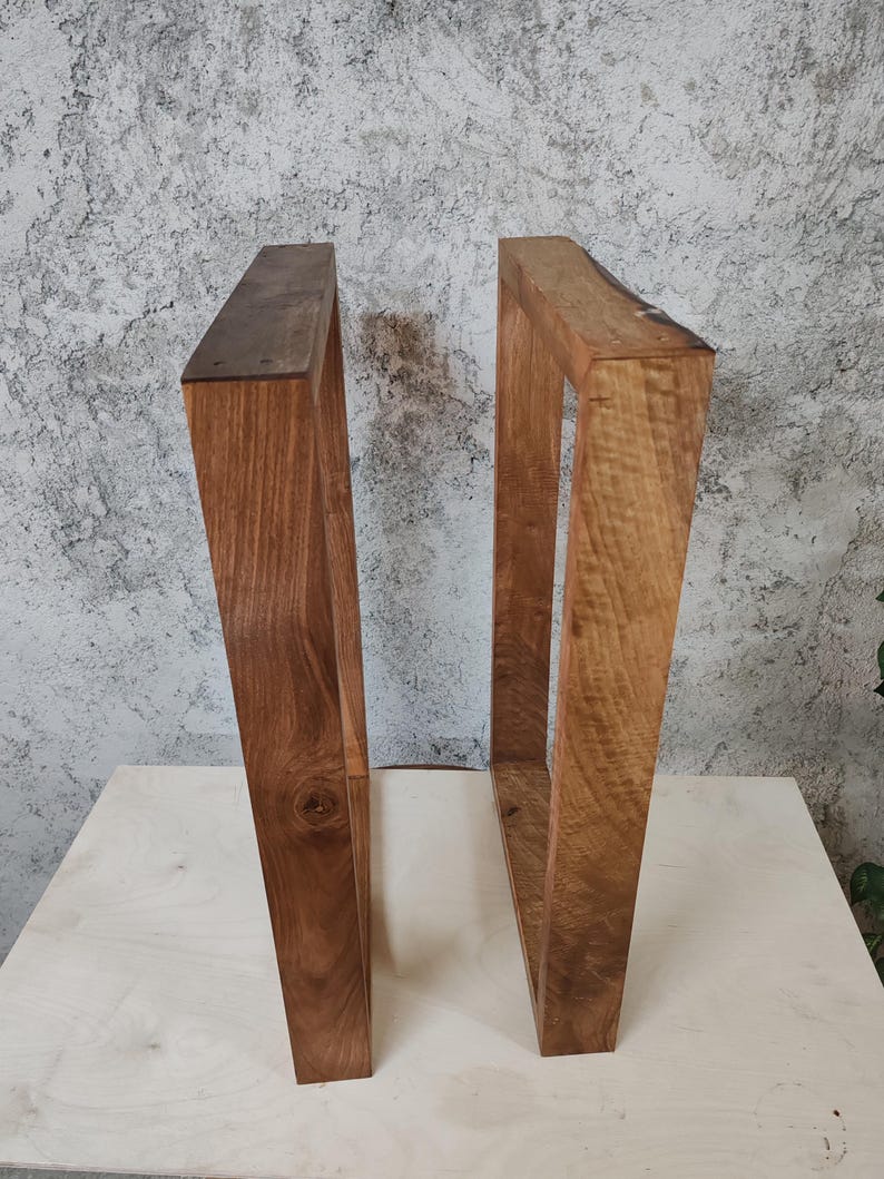 Puede incluir: Dos patas de mesa de madera con un acabado de madera natural. Las patas son de forma rectangular y tienen un aspecto r&uacute;stico.