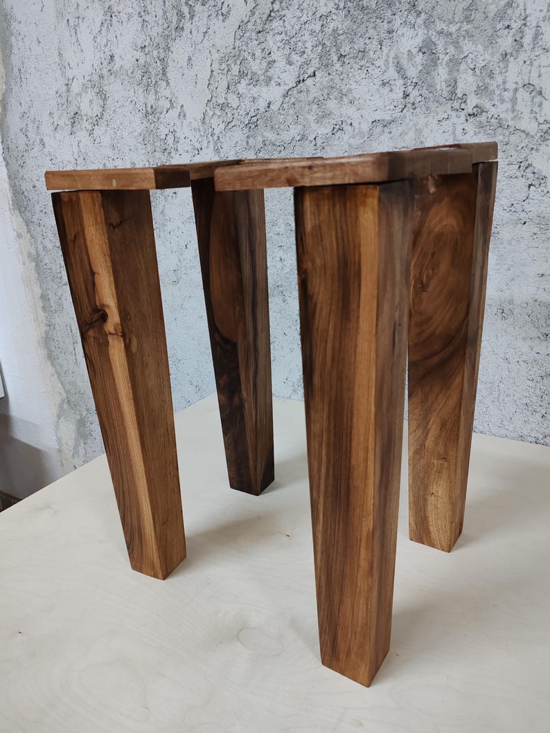 May include: Two wooden stools with a dark brown finish. The stools are made of solid wood and have a simple, modern design.
