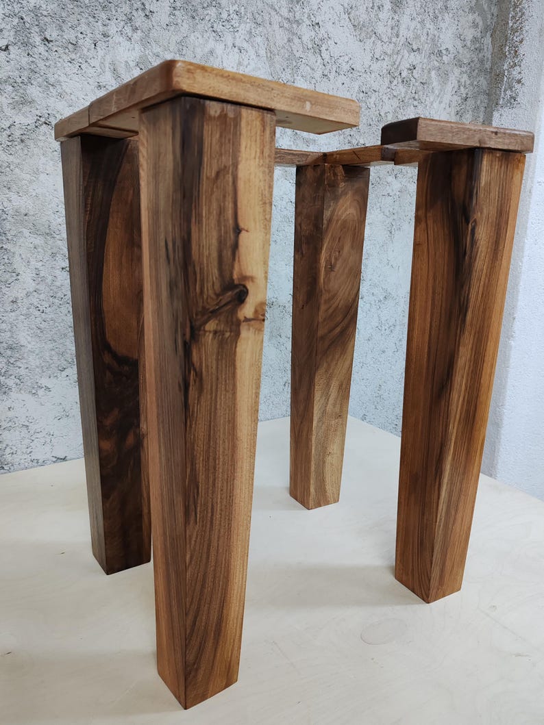 May include: Three wooden legs for a table or stool, made of dark brown wood with a natural finish. The legs are rectangular in shape and have a rustic look.