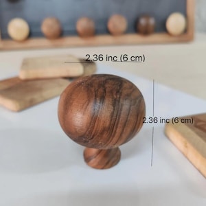May include: A dark brown wooden knob with a round top and a smaller round base. The knob measures 2.36 inches (6 cm) in diameter.